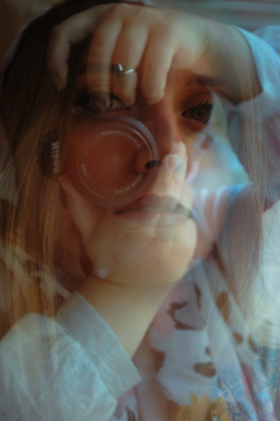 Žena sa pozerá do objektívu fotoaparátu s rukou na hlave.